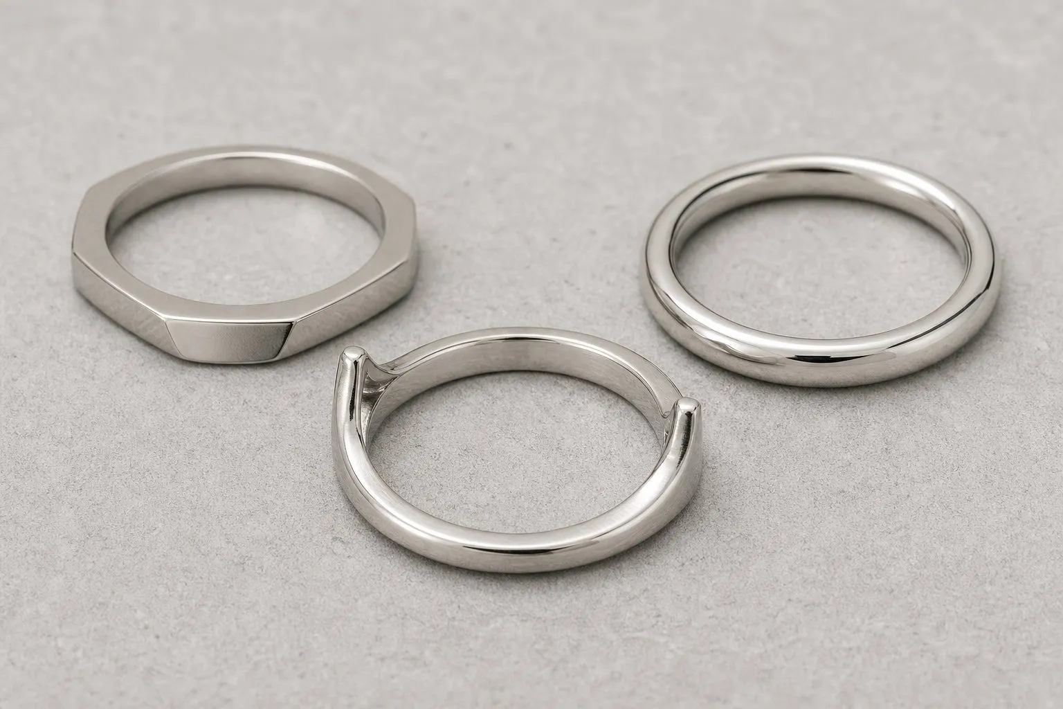Three plain ring shanks with flat, rounded and arched profiles on a gray stone surface